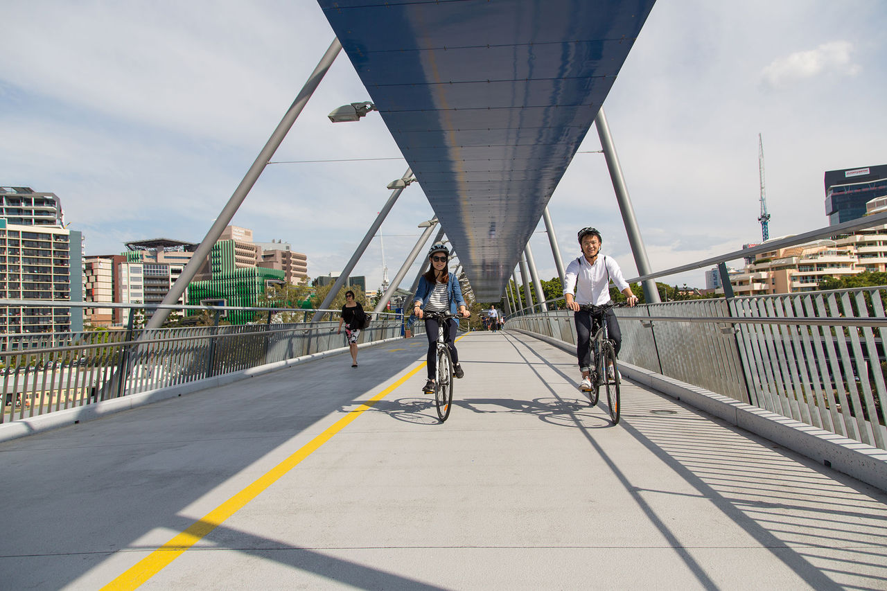 Male and female couple cycling across Goodwill Bridge.