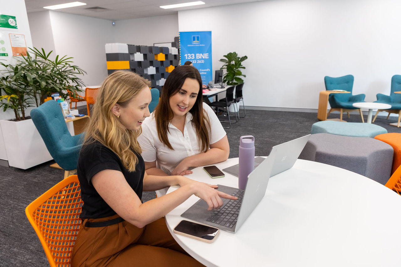 2 women working collaboratively on laptops at the Suburban Business Hub.