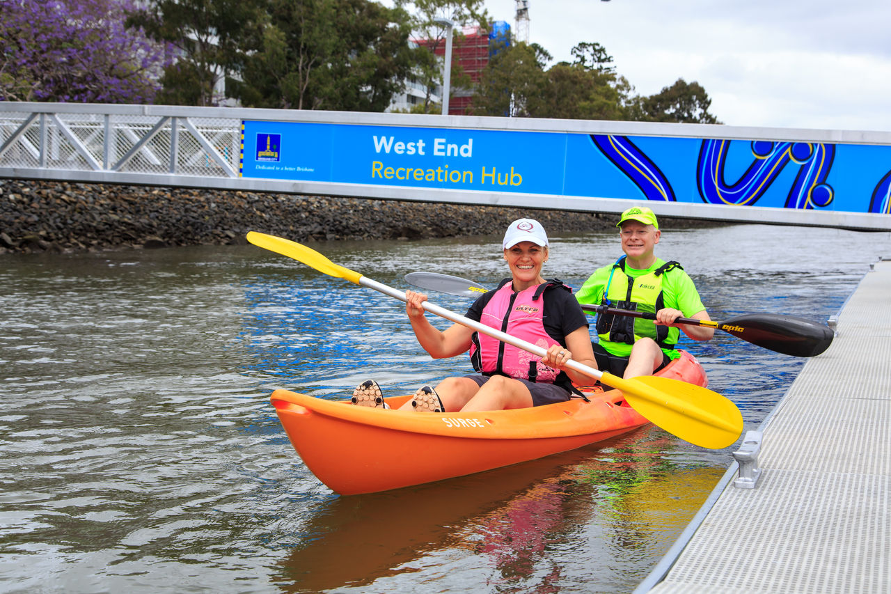 Kayakers pulling away from West End Recreation Hub in an orange Surge kayak.